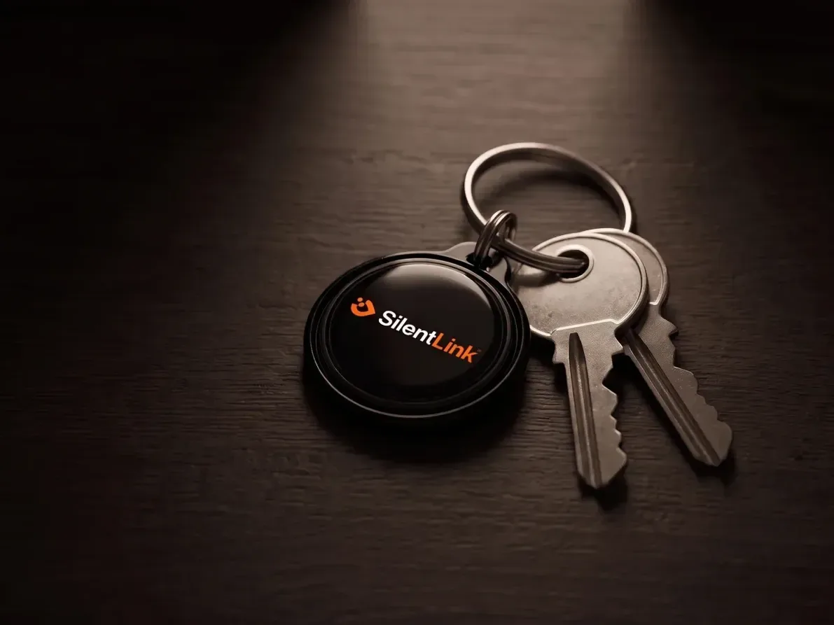 Die KeyID mit zwei Hausschlüsseln auf dunklem Holz, das SilentLink-Logo auf der schwarzen Front