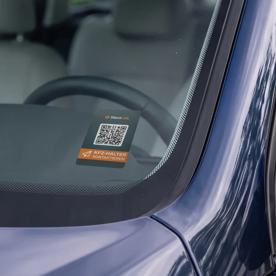 Die DriveID innen an der Windschutzscheibe eines dunkelblauen Autos, dahinter Lenkrad und Sitze